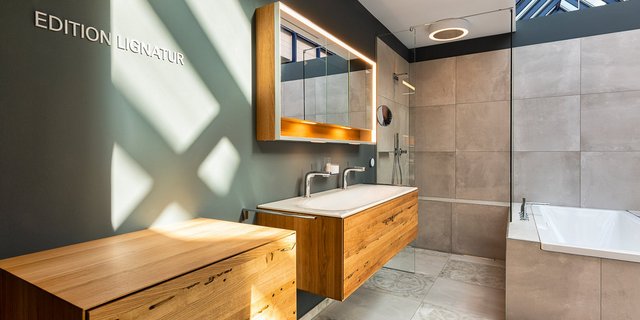 Ein modernes Badezimmer mit eleganten Holzschränken und einem großen Spiegel, der sanft beleuchtet ist.