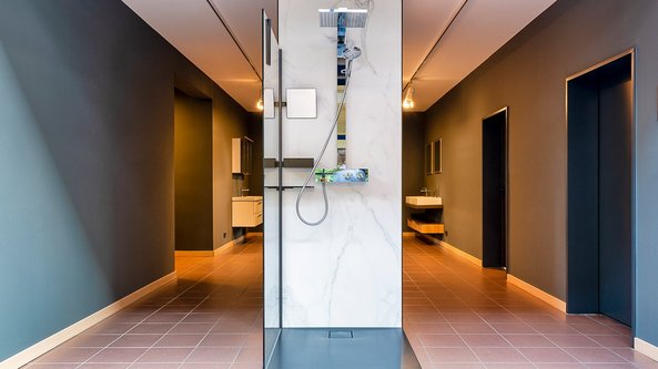 Ein modernes Badezimmer mit einer eleganten Dusche aus Marmor und minimalistischen Wänden in sanften Farben.