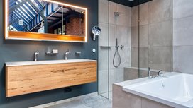 Ein modernes Badezimmer mit einer Holzwaschtischplatte, einem großen Spiegel und einer eleganten Dusche aus Glas.