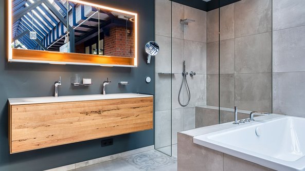 Ein modernes Badezimmer mit einer Holzwaschtischplatte, einem großen Spiegel und einer eleganten Dusche aus Glas.