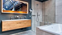 Ein modernes Badezimmer mit einer Holzwaschtischplatte, einem großen Spiegel und einer eleganten Dusche aus Glas.