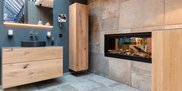 Ein modernes Badezimmer mit einem eleganten Holzwaschtisch und einem stilvollen, eingebauten Kamin, der Holzscheite zeigt.
