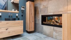 Ein modernes Badezimmer mit einem eleganten Holzwaschtisch und einem stilvollen, eingebauten Kamin, der Holzscheite zeigt.
