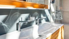 Ein modernes Badezimmer mit einem eleganten Waschbecken aus weißem Porzellan und glänzenden Armaturen, umgeben von Holzdetails.