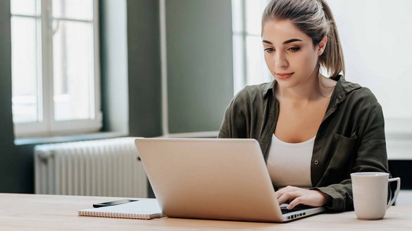 Eine junge Frau die an einem Laptop sitzt 