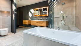 Ein modernes Badezimmer mit einer freistehenden Badewanne, eleganten Holzschränken und einer großen, gläsernen Dusche.